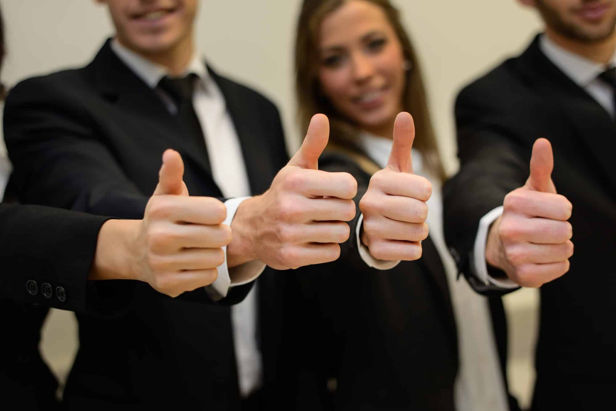 Business team holding their thumbs up