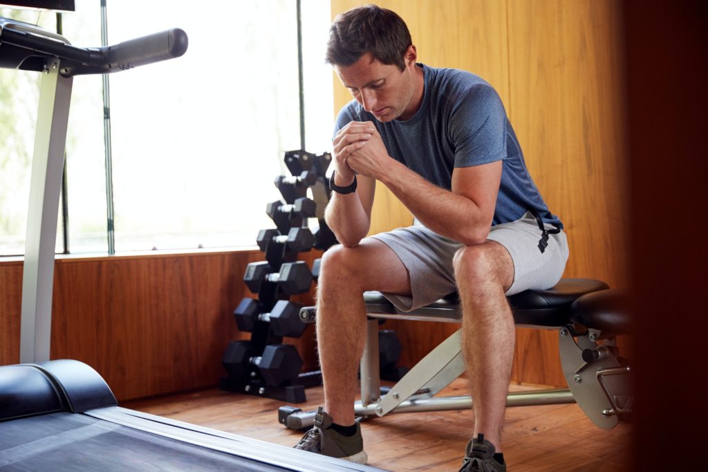 homme anxieux assis sur une machine de salle de sport