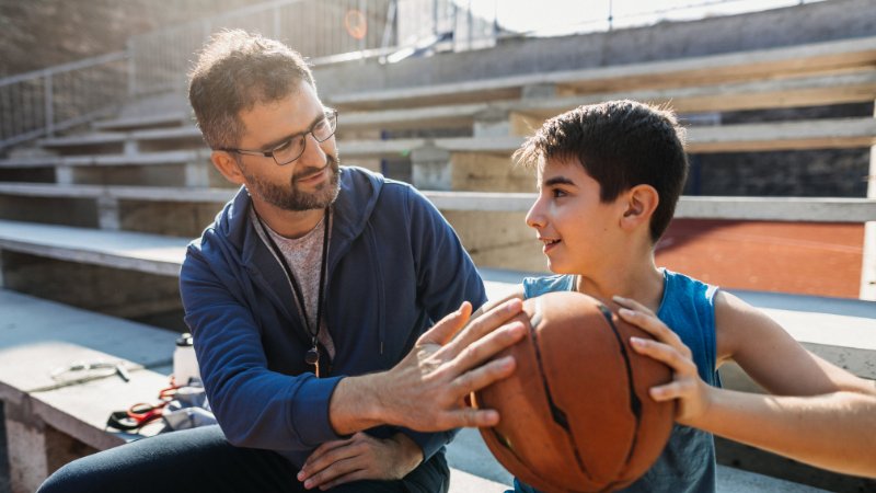 Un coach qui apprend les bases de la préparation mentale en basketball à son joueur
