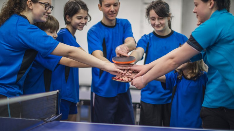 Un coach avec ses joueurs et joueuses à la fin d'une séance de préparation mentale tennis de table