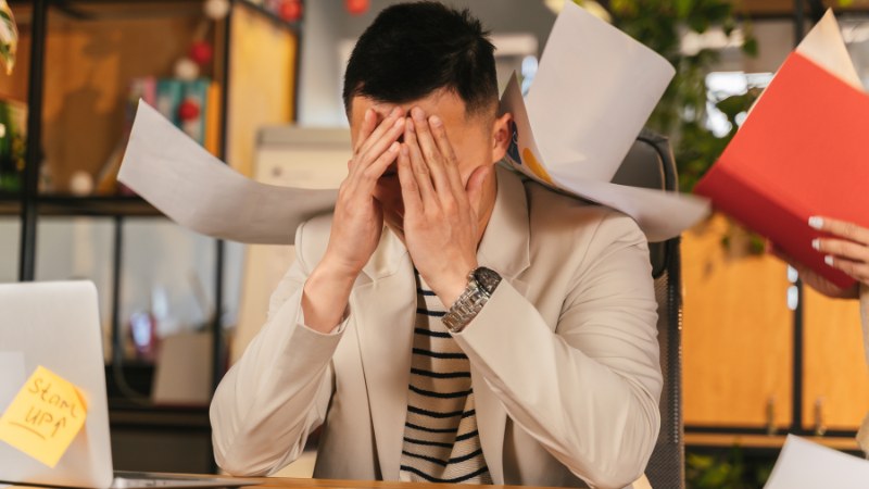 Un homme sous pression au travail à cause du syndrome de l'imposteur et de la procrastination