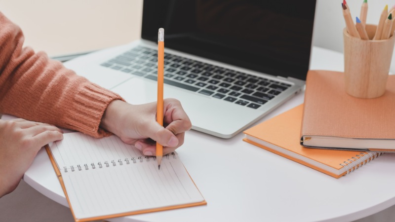Une personne avec un syndrome de l'imposteur qui note toutes ses réussites passées sur papier